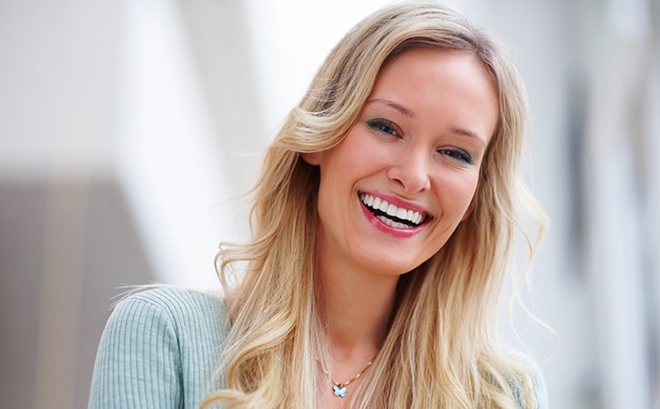 A blonde woman with perfect teeth smiling after her Dillingham Hanson visit