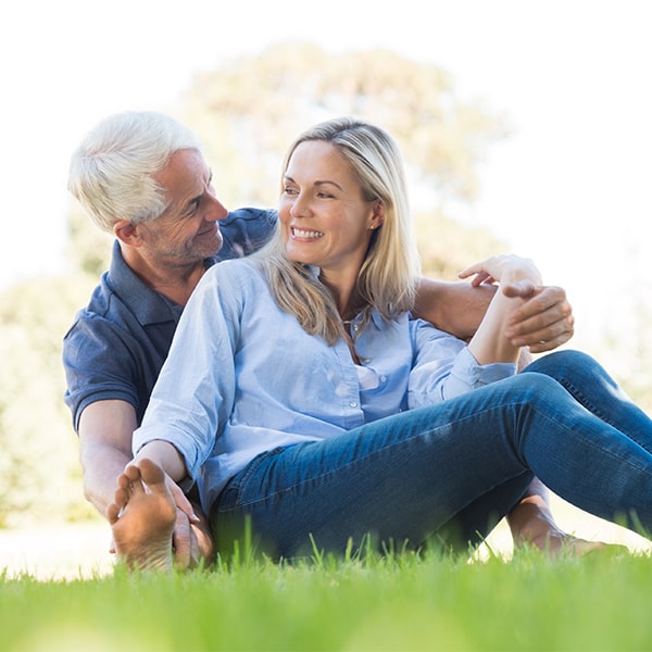 Older couple sitting on grass after a root canal at Dillingham Hanson